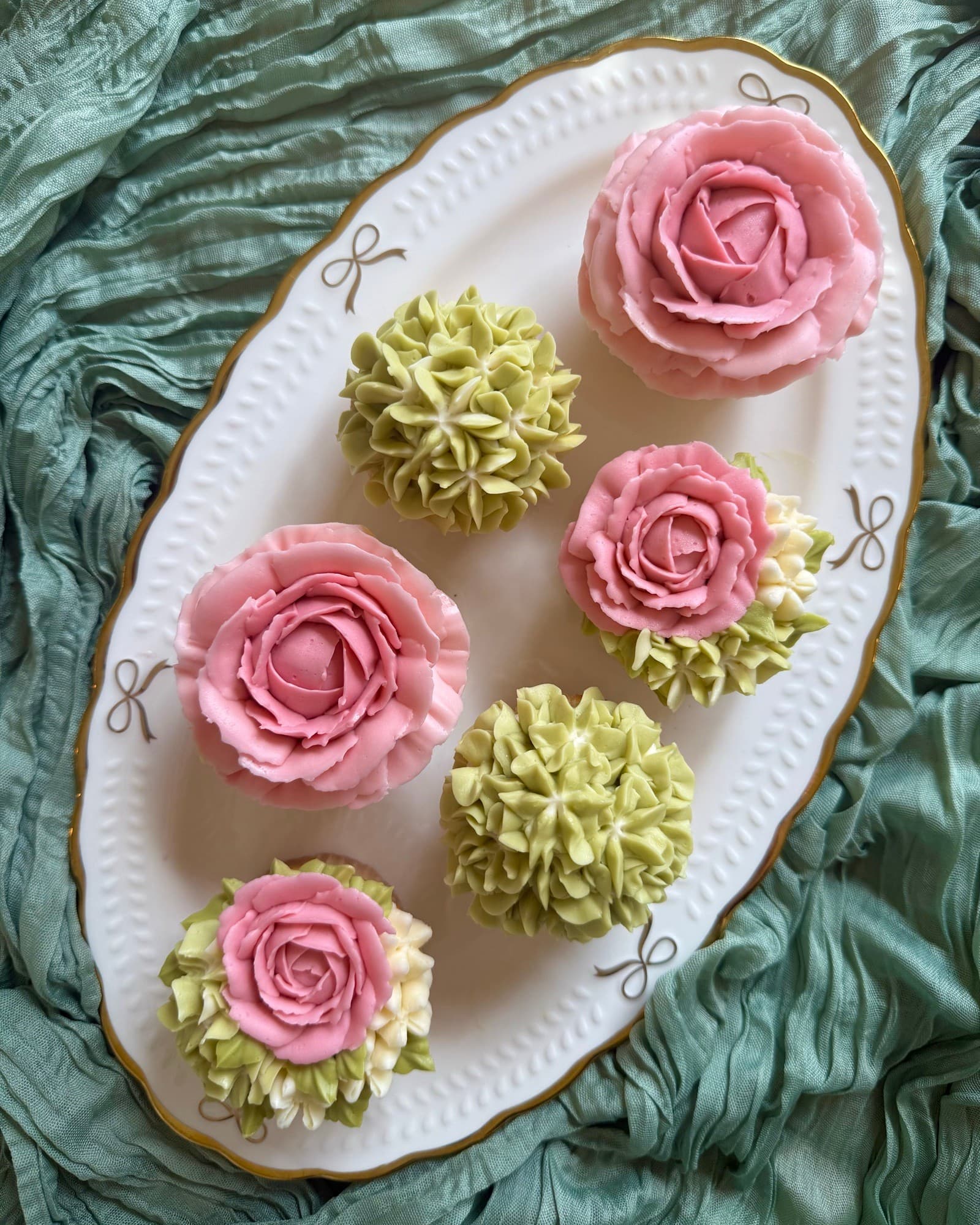 Pink rose and pale green hydrangea cupcakes on a white oval platter