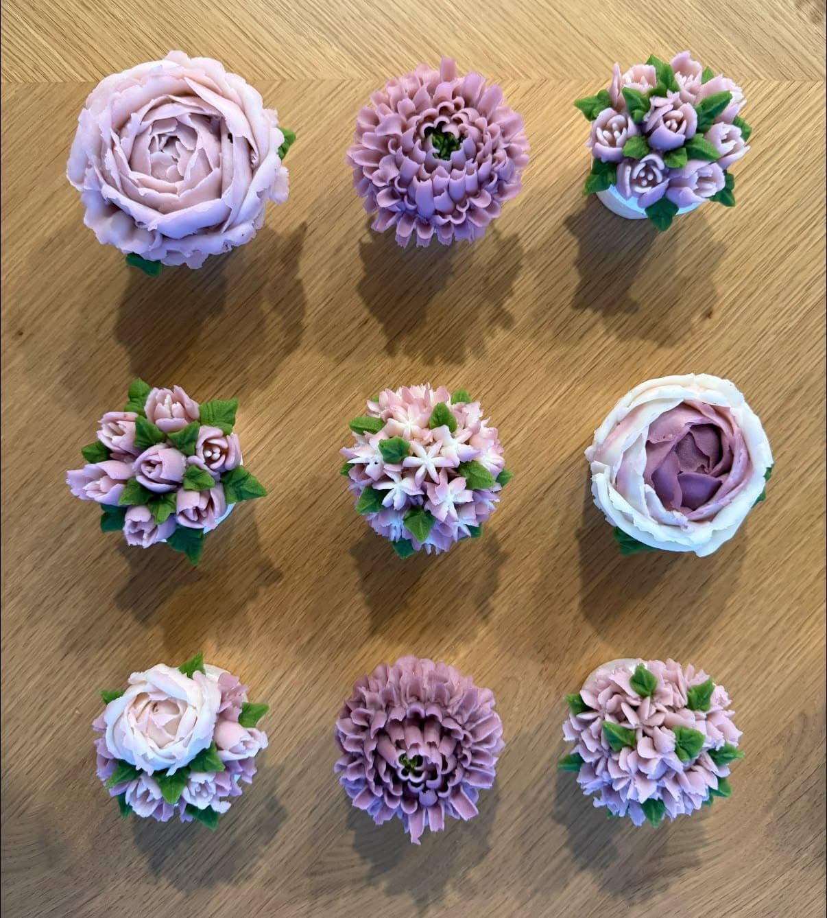 Nine cupcakes in lilac and lavender: peonies, dahlias and clusters of rosebuds