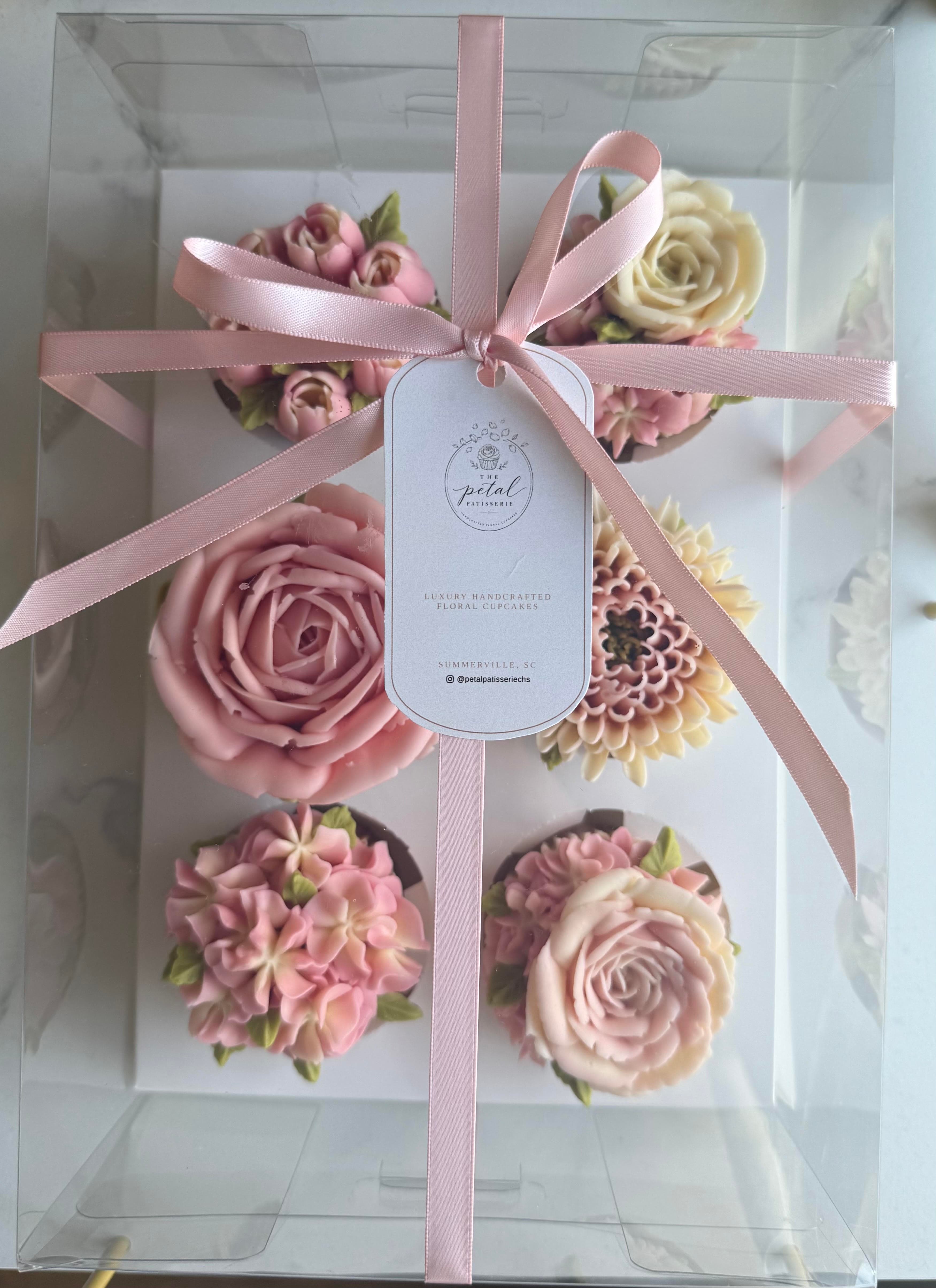A box of six floral cupcakes in soft pinks